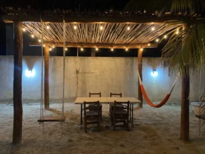 Pergola rustica de troncos con hamaca columpio comedor e iluminada con guirnalda