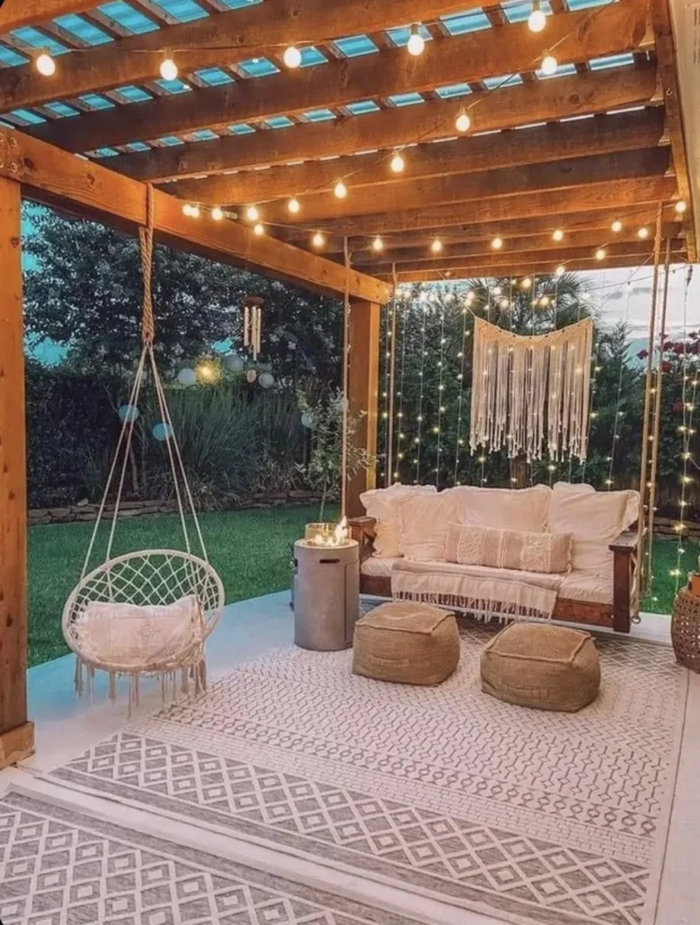 Cenador de madera con sofá suspendido, silla de macramé colgante, guirnaldas de luces y decoración de pared en hilo blanco. Cenador de madera con sofa suspendido silla de macrame colgante guirnaldas de luces y decoracion de pared en hilo blanco