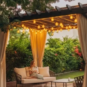 Pérgola elegante para jardín con cortinas decorativas y luces cálidas